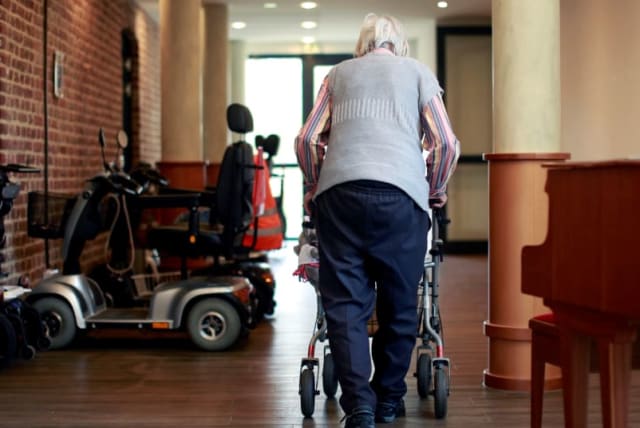  Una anciana camina por el pasillo de una residencia de ancianos cuyas visitas se han restringido debido a la preocupación que suscita la enfermedad por coronavirus (COVID-19), en Grevenbroich. (photo credit: REUTERS)