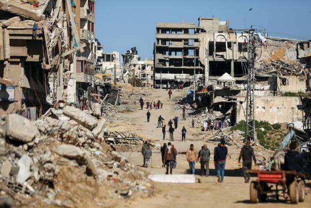  PALESTINIANS WALK past the ruins of houses destroyed during the Gaza war, in Gaza City, last month.  (photo credit: REUTERS/DAWOUD ABU ALKAS)