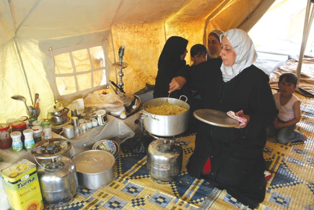  A REFUGEE COOKS inside a tent in the Al-Hawl refugee camp, in northern Syria, in this file photo.  (photo credit: REUTERS/KHALED AL-HARIRI)