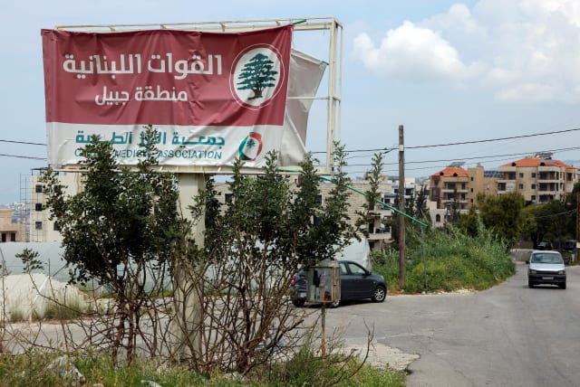  A car drives past a billboard that reads: ' The Lebanese Forces. Byblos area', in Byblos, Lebanon April 8, 2024. (photo credit: REUTERS/MOHAMED AZAKIR)