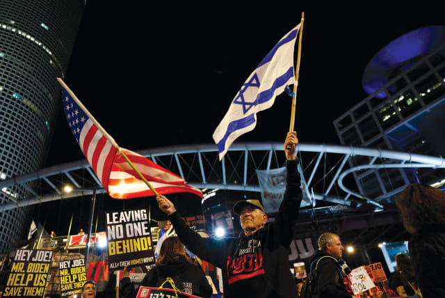  A demonstrator holds American and Israeli flags during a protest calling for the release of hostages, Tel Aviv on March 9. (photo credit: REUTERS/CARLOS GARCIA RAWLINS)