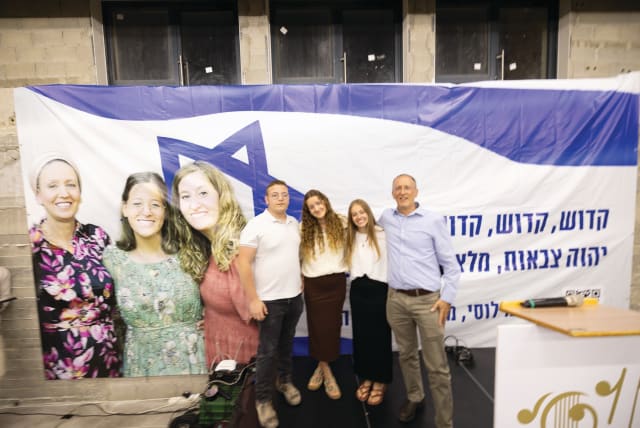  SHIRAT LUCY: Yehuda, Keren, Tali, and Rabbi Leo Dee in front of a portrait of Lucy, Rina, and Maia, at the first yahrzeit event, April 7. (photo credit: Yacov Segal)