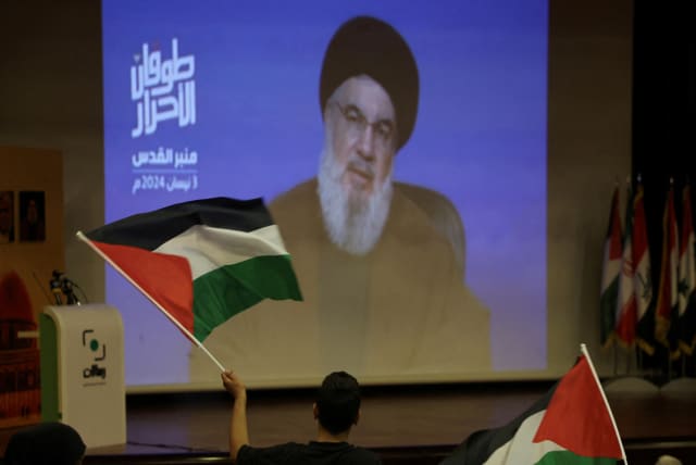   A man holds a Palestinian flag as Lebanon's Hezbollah leader Sayyed Hassan Nasrallah speaks in a pre-recorded message shown on a screen during an event ahead of Al-Quds (Jerusalem) Day on Friday April 5, in Beirut, Lebanon April 3, 2024.  (photo credit: REUTERS/MOHAMED AZAKIR/FILE PHOTO)