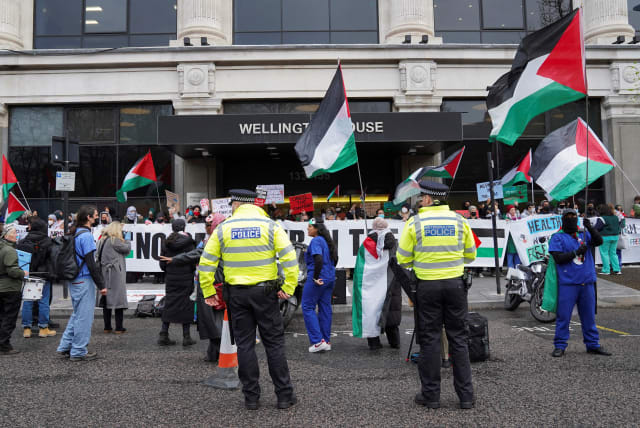  Police officers stand guard as National Health Service (NHS) workers protest outside Wellington House against the contract NHS has with Palantir Technologies UK, amid the ongoing conflict between Israel and the Palestinian Islamist group Hamas, in London, Britain April 3, 2024.  (photo credit: REUTERS/Maja Smiejkowska)