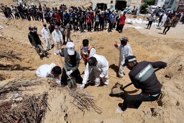 People work to move into a cemetery bodies of Palestinians killed during Israel's military offensive and buried at Nasser hospital, amid the ongoing conflict between Israel and Hamas, in Khan Yunis in the southern Gaza Strip, April 21, 2024. (photo credit: REUTERS/Ramadan Abed)