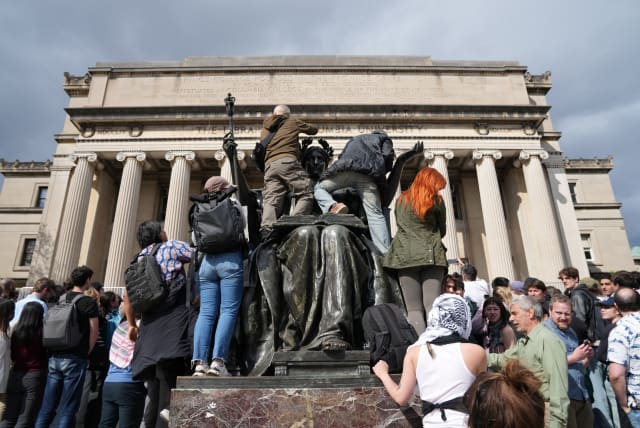  People climb the Alma Mater statue to see the speaker of the U.S. House of Representatives Mike Johnson (R-LA) during a press conference at Columbia University in response to demonstrators protesting in support of Palestinians, amid the ongoing conflict between Israel and the Palestinian Islamist g (photo credit: REUTERS/DAVID 'DEE' DELGADO)