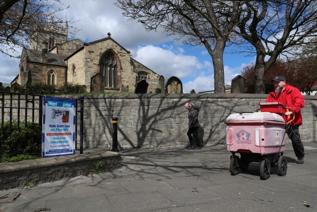  People walk past an election poster ahead of tomorrow's local elections, in Hartlepool, Britain May 5, 2021.