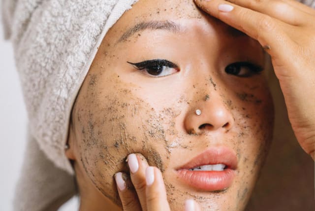 A woman is seen putting exfoliants on her face. (photo credit: PEXELS)