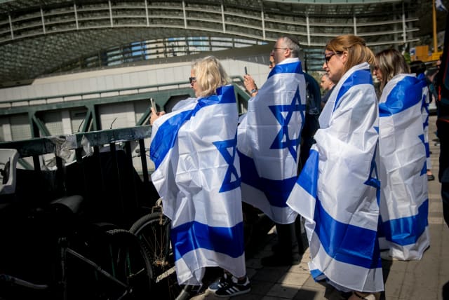 People stand still in Tel Aviv, as a two-minute siren is sounded across Israel to mark Holocaust Remembrance Day on May 6, 2024 (photo credit: MIRIAM ALSTER/FLASH90)