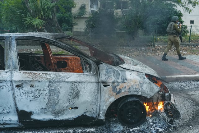  A SOLDIER passes by a burned-out car in Kiryat Shmona in the aftermath of a rocket attack on the northern Israeli city, earlier this month. Since the conflict began, northern Israel has come under repeated rocket and drone attacks from Lebanon, the writer notes. (photo credit: AYAL MARGOLIN/FLASH90)