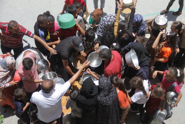  Palestinians gather to receive food cooked by a charity kitchen as the conflict between Israel and Hamas continues, in Jabalya refugee camp, in the northern Gaza Strip, June 19, 2024. (photo credit: Mahmoud Issa/Reuters)