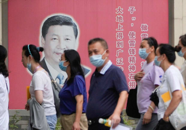  People wearing masks pass by portraits of Chinese President Xi Jinping, following the coronavirus disease (COVID-19) outbreak, in Shanghai, China, August 31, 2022