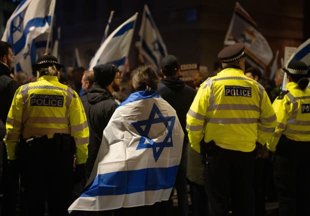 A woman draped in an Israeli flag stands next to police officers as she joins members of the Jewish community outside BBC Broadcasting House to demonstrate against the BBC's ongoing refusal to label Hamas as terrorists, in London, England, October 16, 2023; file photo.