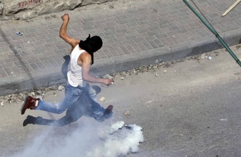 Palestinian kicking back a tear gas canister in Silwan GALLE
