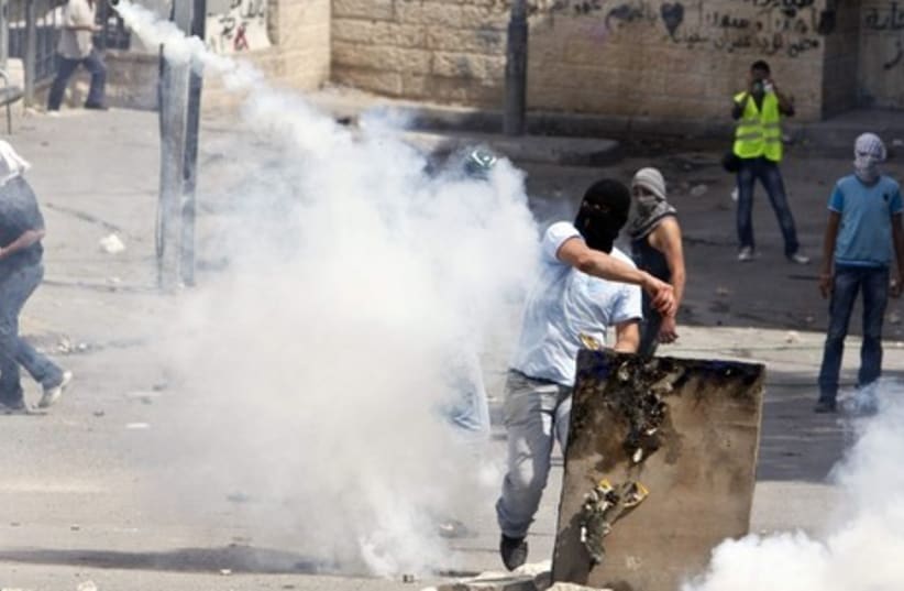 Palestinian throwing back a tear gas canister in Silwan GALL