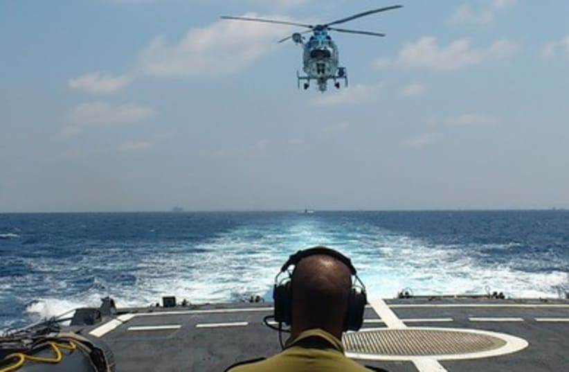 Navy sailor guides a helicopter set to land