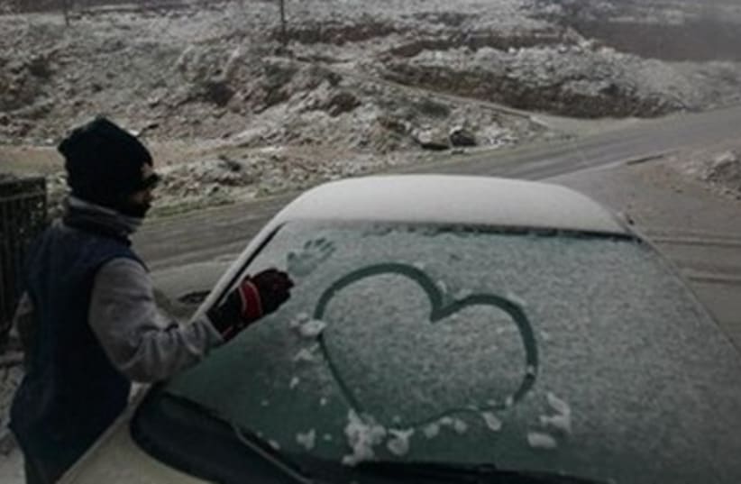A Druze boy draws a handprint on a snowy car windsheild 390