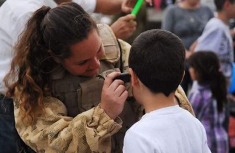 Boy gets face painted by IDF soldier 390