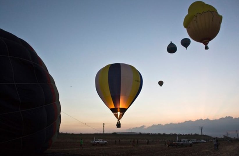 Hot air balloons fly overhead during sunrise 