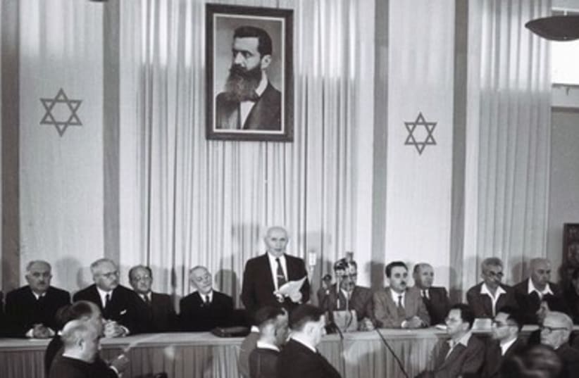ISRAEL’S FIRST prime minister David Ben-Gurion (center) stands under a portrait depicting Theodore Herzl, the father of modern Zionism, as he reads Israel’s Declaration of Independence in Tel Aviv May 14, 1948. 