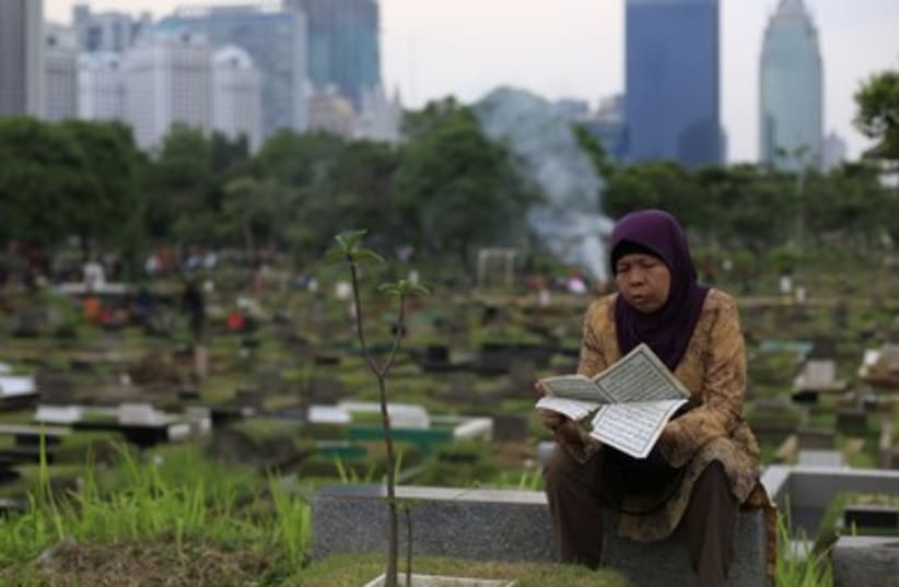 A woman reads the Koran at her husband's grave in a cemetery, ahead of the Islamic holy fasting month of Ramadan, in Jakarta.