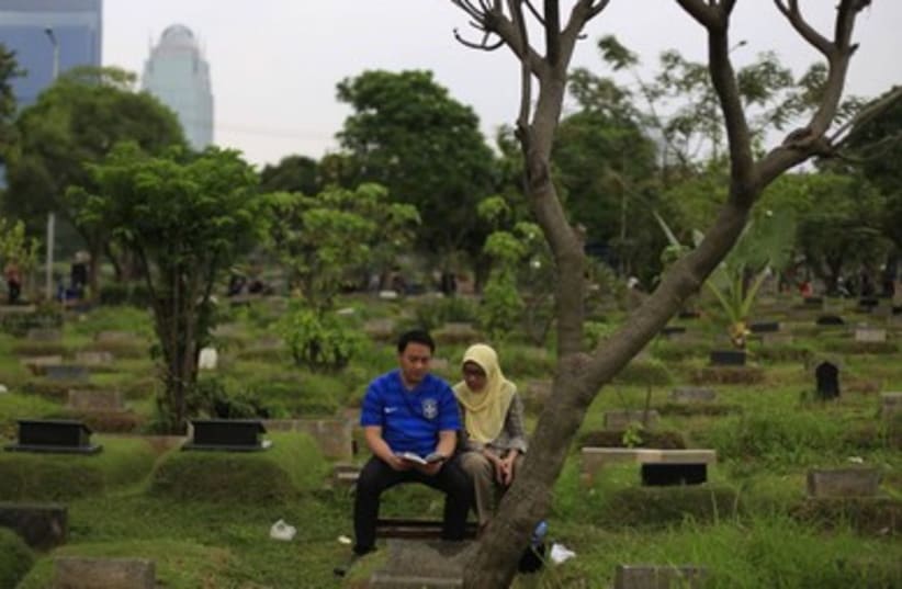 A couple reads the Koran at a relative's grave in a cemetery, ahead of the Islamic holy fasting month of Ramadan, in Jakarta.