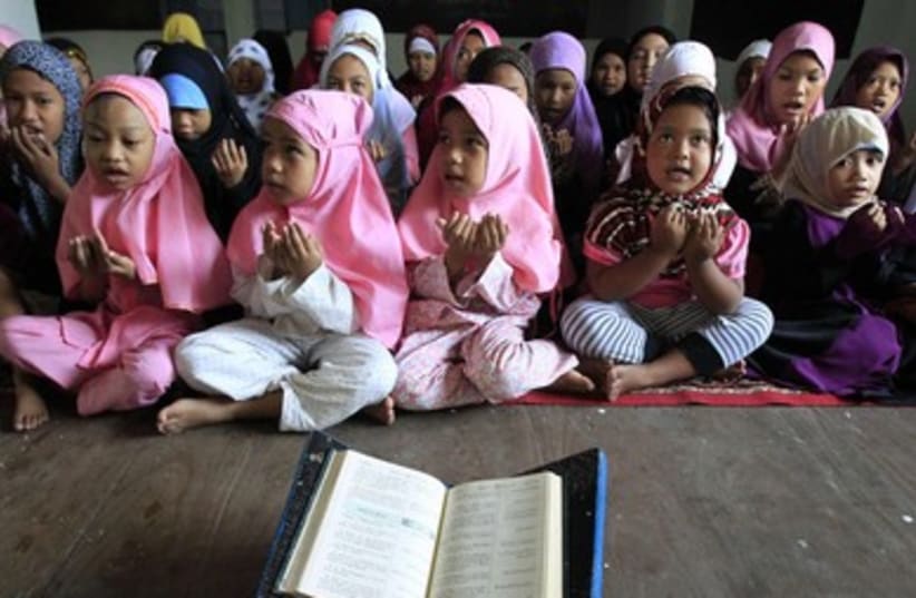 Filipino Muslim students hold a prayer before starting to read the Koran during the holy fasting month of Ramadan in Baseco, Tondo city.