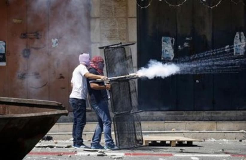 Palestinians set off firecrackers towards Israeli police during clashes in Shuafat.