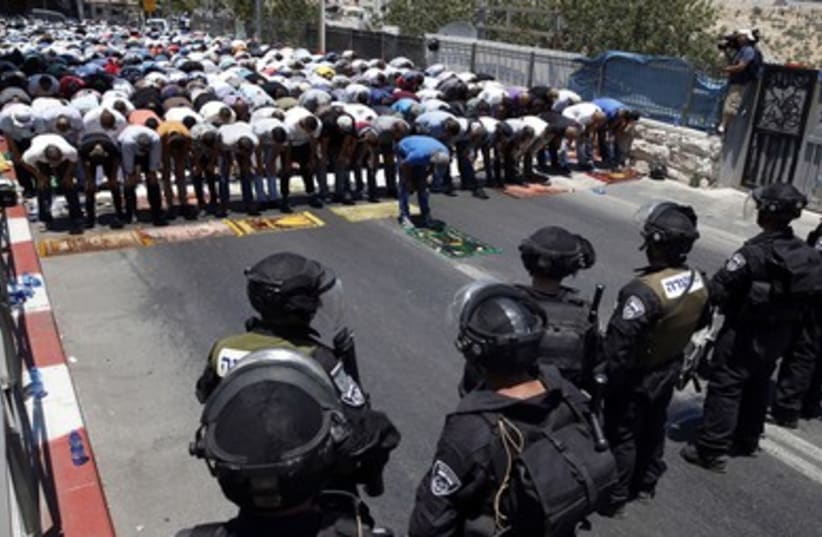 Palestinians in the Wadi al-Joz section of east Jerusalem pray on the first Friday of Ramadan as Israeli police look on.