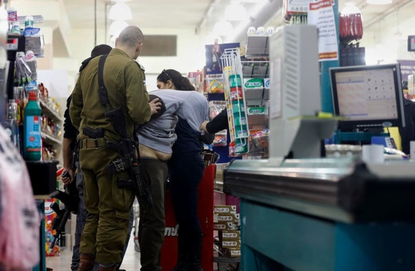 Israeli police forces detain a suspected Palestinian at a supermarket, where another Palestinian stabbed two people, December 3