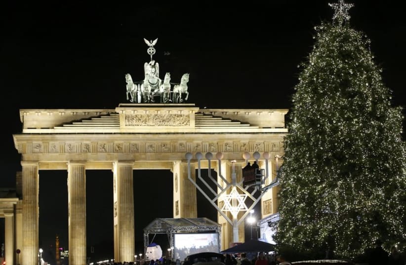 A giant menorah stands next to a Christmas tree in front of the Brandenburg gate to celebrate Hanukkah in Berlin