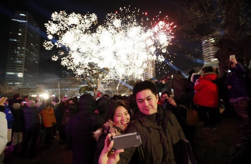 A couple takes a selfie as fireworks go off in the background in Seoul