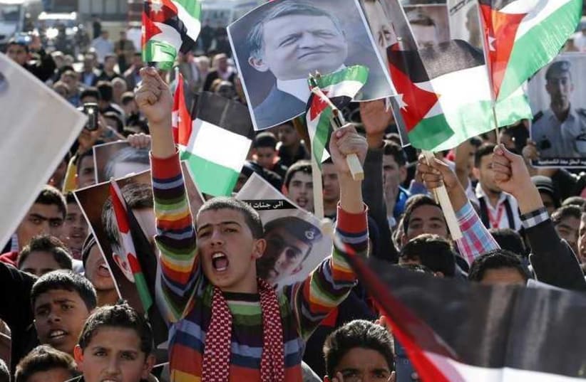 Protesters hold up pictures of Jordan's King Abdullah and pilot Muath al-Kasaesbeh as they chant slogans during a rally in Amman