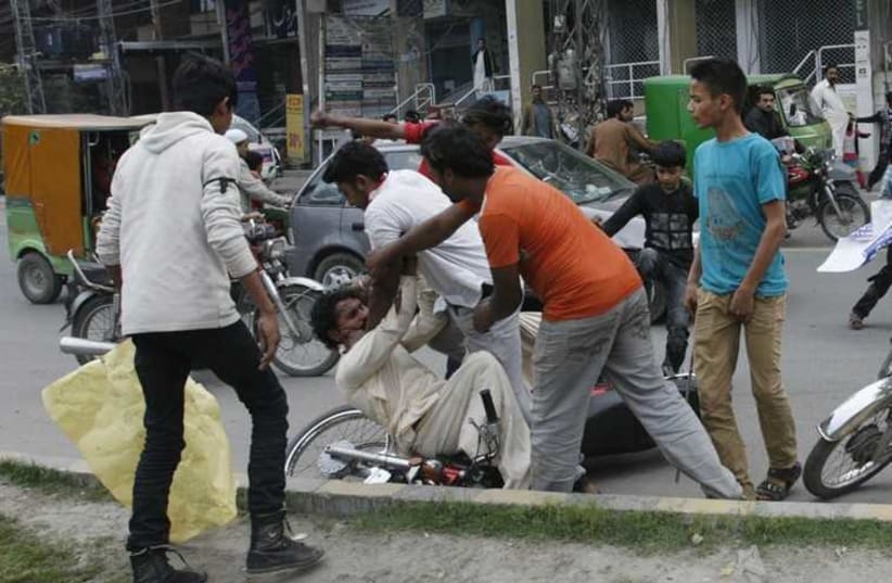 People from the Christian community beat a motorist who refuses to respect a road block after twin blast attacks on two churches in Lahore March 15, 2015.