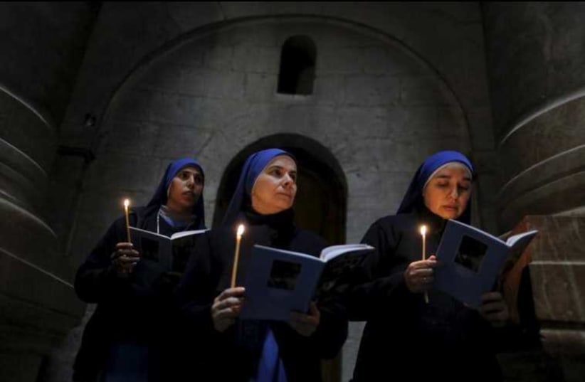 Catholic nuns hold candles as they take part in the Washing of the Feet ceremony in the Church of the Holy Sepulchre in Jerusalem's Old City