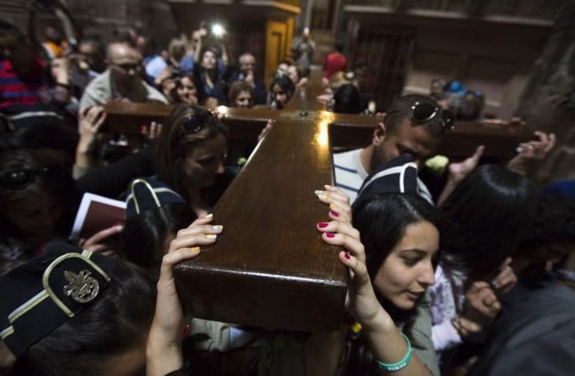 Christians carry a cross after a procession in the Church of the Holy Sepulchre on Good Friday, during Holy Week in Jerusalem's Old City