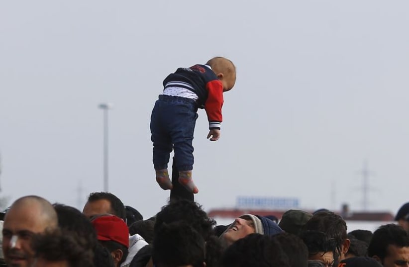 A man holds a baby over the crowd as migrants wait for busses at the crossing point between Hungary and Austria in Nickelsdorf, Austria