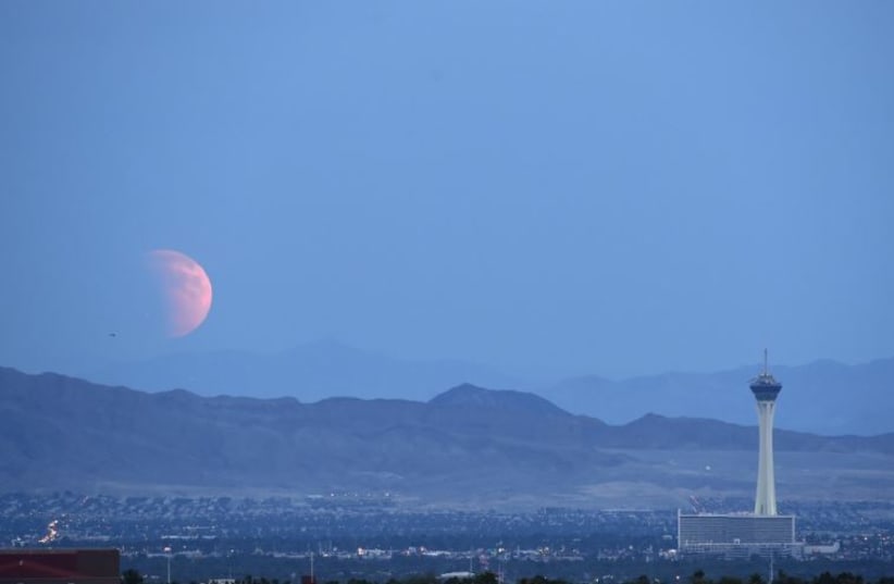 A partially eclipsed supermoon, the last of this year's supermoons, rises over Las Vegas