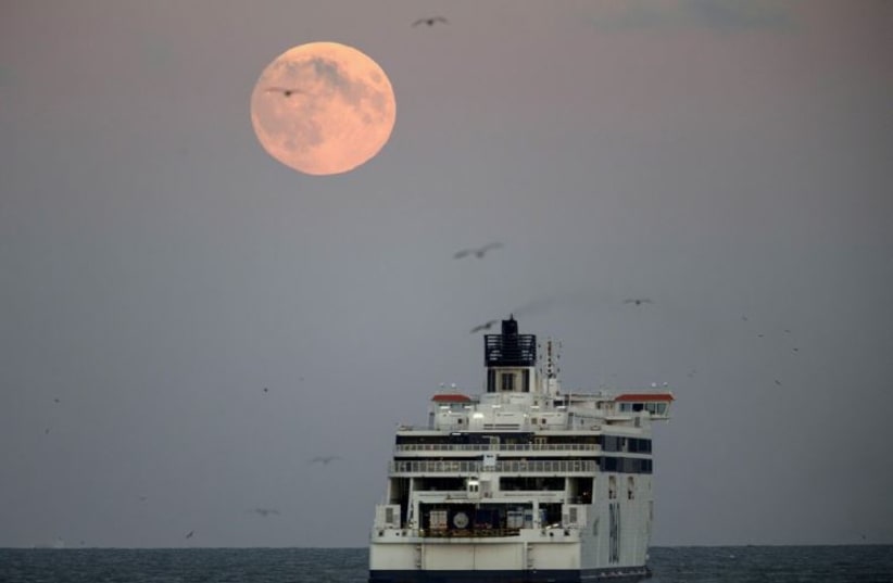 The moon is seen above a cross channel ferry leaving the port of Dover, southern England