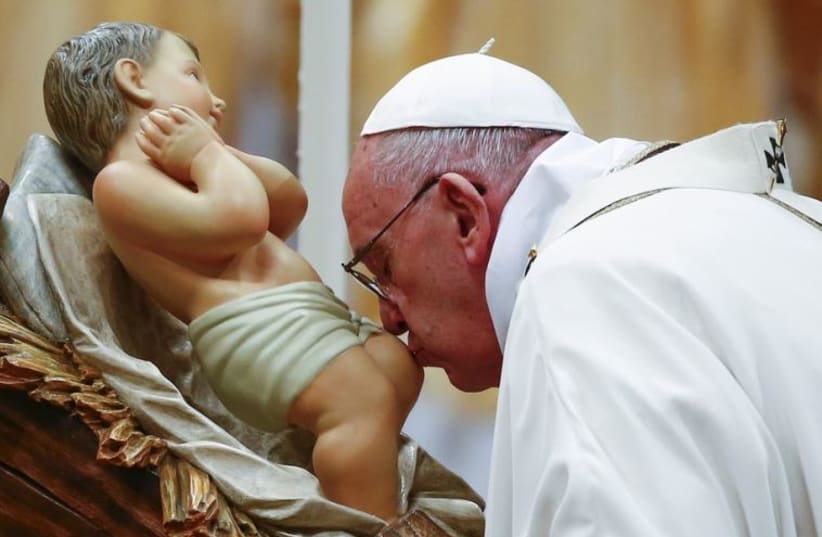 Pope Francis kisses a statue of baby Jesus as he leads the Christmas night Mass in Saint Peter's Basilica at the Vatican 