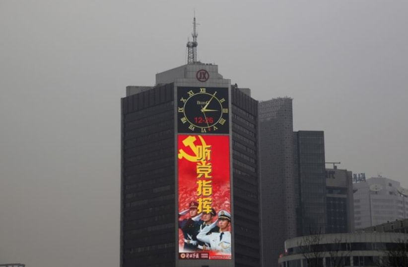 A large screen on a building shows a propaganda image of the Chinese People's Liberation Army on a heavily polluted day in Beijing