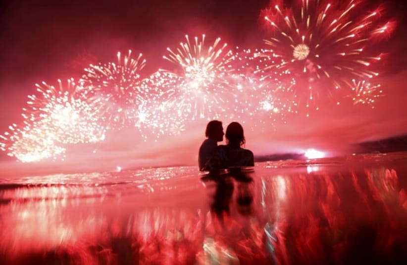 A couple watch as fireworks explode over Copacabana beach during New Year celebrations in Rio de Janeiro